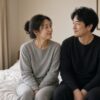 無地の上下ルームウェアを着て寝室でくつろぐ40代の夫婦